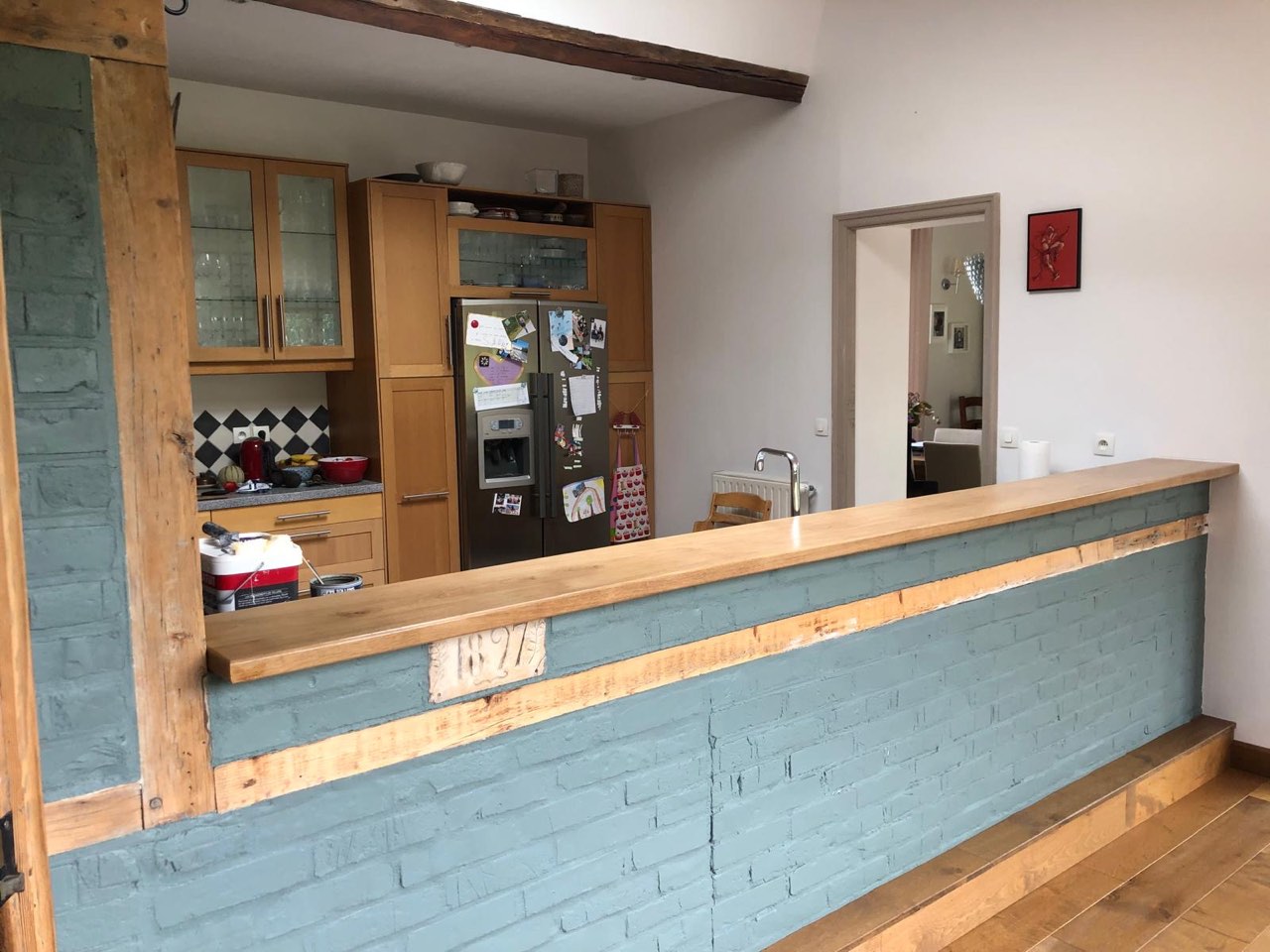 Bar séparant la cuisine du séjour, soubassement en briques peintes et plan de travail en bois — chantier à Honfleur