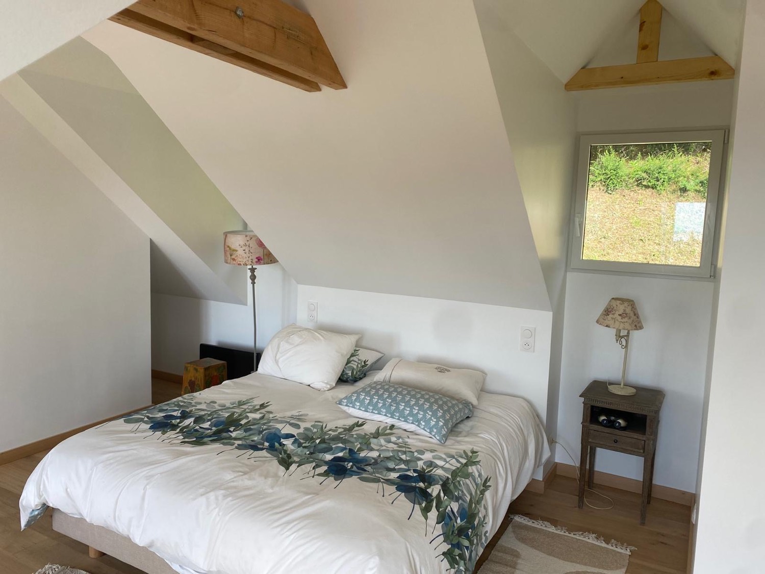Chambre mansardée fraîchement repeinte avec fenêtre neuve et parquet chêne