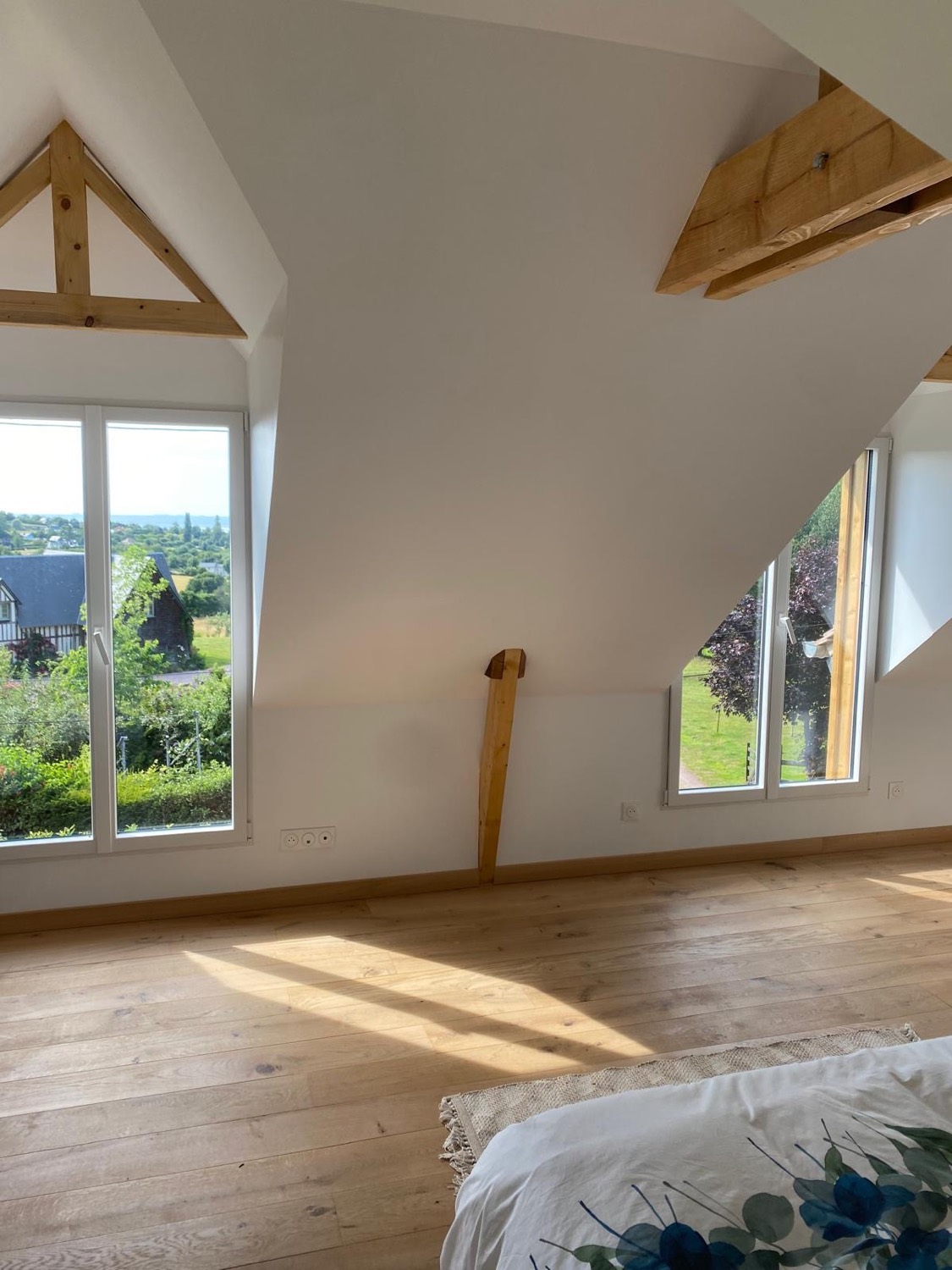 Suite sous combles avec charpente bois, fenêtres neuves et vue sur le paysage normand à Bourg-Achard