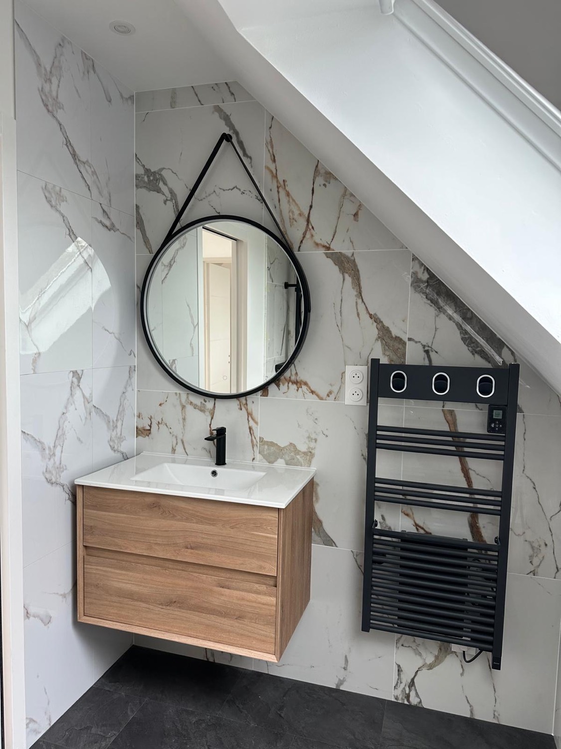 Salle d'eau sous combles avec faïence marbrée, meuble vasque bois et miroir rond — chantier à Villers-sur-Mer