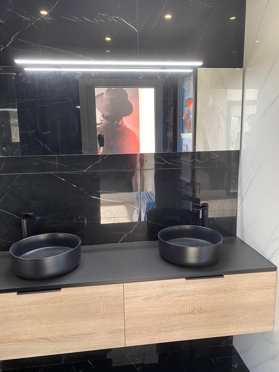 Salle de bain en marbre noir avec double vasque ronde noire sur meuble bois et miroir rétroéclairé — chantier à Deauville